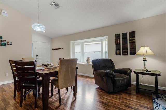 dining space with lofted ceiling, dark wood-type flooring, and a textured ceiling