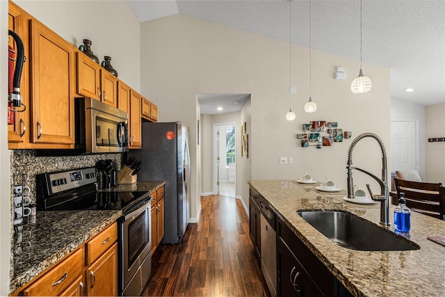 kitchen featuring appliances with stainless steel finishes, sink, hanging light fixtures, and light stone counters