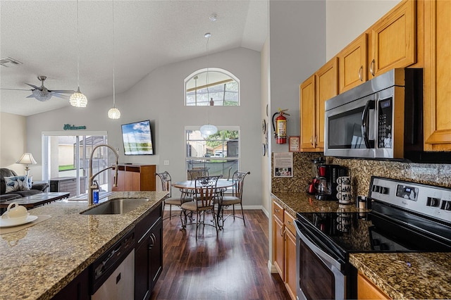 kitchen featuring a textured ceiling, appliances with stainless steel finishes, sink, and dark stone counters