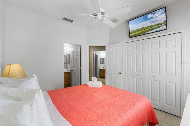 bedroom with ensuite bath, a textured ceiling, a closet, ceiling fan, and light tile patterned floors