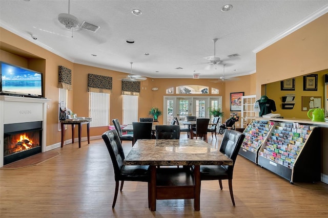 dining area with ornamental molding, a textured ceiling, and light wood-type flooring