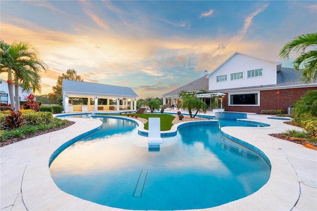 pool at dusk featuring a patio area