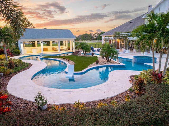 pool at dusk featuring a patio area, a gazebo, and an in ground hot tub