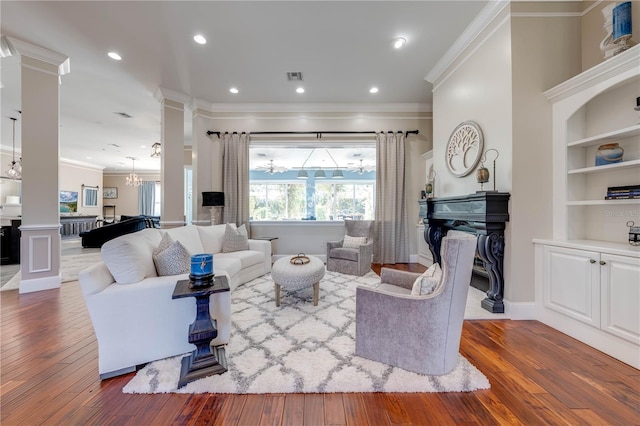 living room featuring dark wood-type flooring, built in features, ornate columns, and crown molding