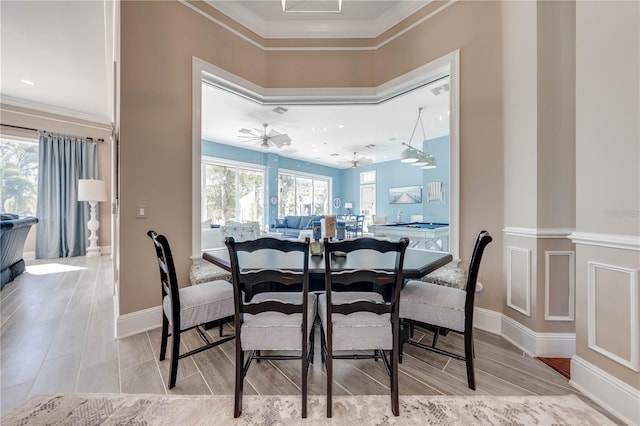 dining space featuring ornamental molding, wood-type flooring, ceiling fan, and decorative columns