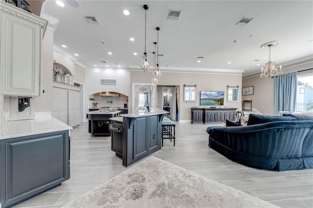 kitchen with pendant lighting, an inviting chandelier, a kitchen bar, and a kitchen island with sink