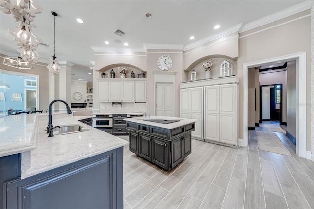 kitchen featuring light hardwood / wood-style floors, sink, oven, white cabinetry, and a large island with sink