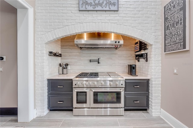 kitchen with gray cabinets, double oven range, backsplash, and exhaust hood