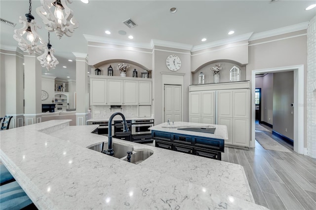 kitchen featuring a large island, white cabinetry, sink, and light stone counters