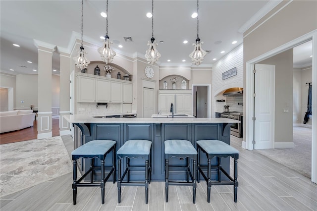 kitchen featuring a large island, a kitchen breakfast bar, decorative light fixtures, and ornate columns