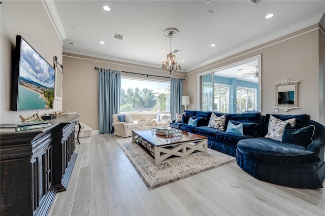 living room with light wood-type flooring, ceiling fan with notable chandelier, and crown molding