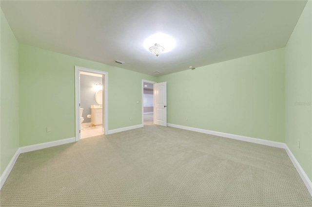 unfurnished bedroom featuring light colored carpet and ensuite bath