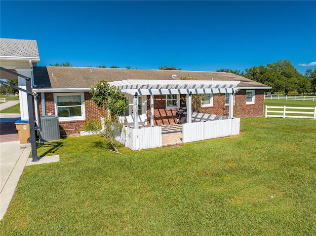 exterior space with central air condition unit, a pergola, a lawn, and a patio area