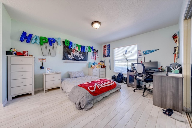 bedroom with light hardwood / wood-style floors and a textured ceiling