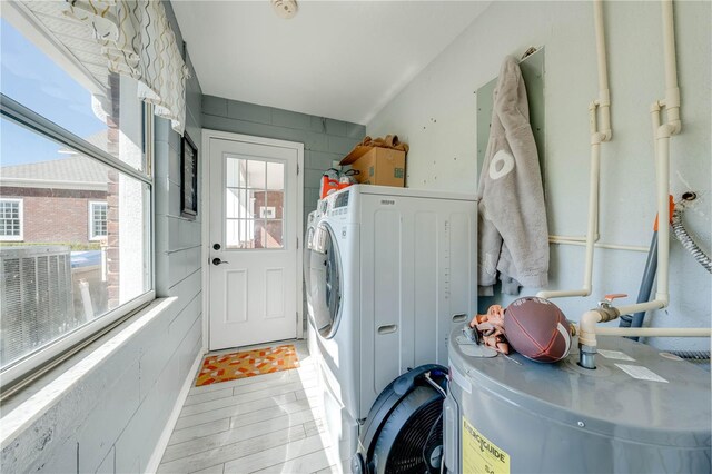 clothes washing area featuring light wood-type flooring, water heater, and washer / dryer