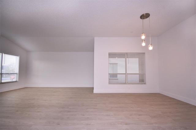 spare room featuring a textured ceiling and light hardwood / wood-style floors