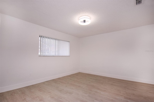 empty room with a textured ceiling and light wood-type flooring