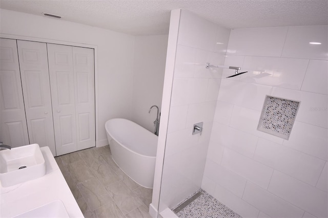 bathroom featuring vanity, separate shower and tub, and a textured ceiling