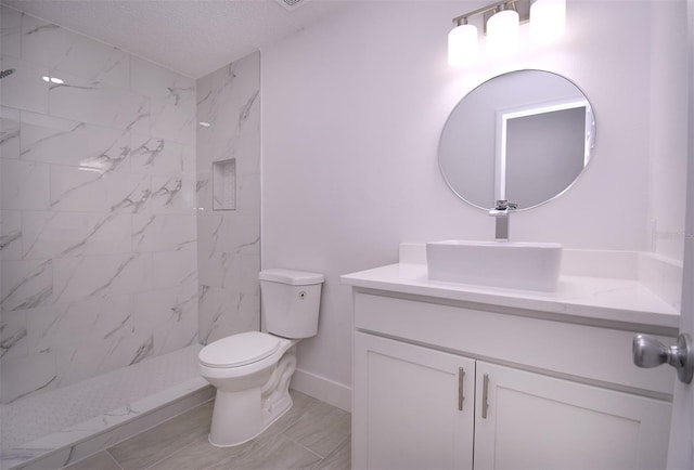 bathroom with vanity, tiled shower, a textured ceiling, and toilet