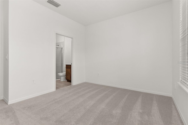 unfurnished bedroom featuring connected bathroom, a spacious closet, and light colored carpet