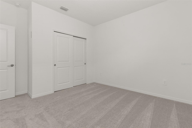 unfurnished bedroom featuring light colored carpet and a closet