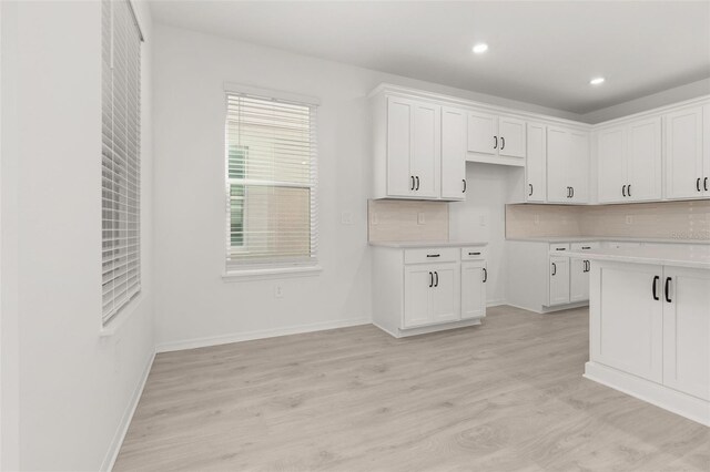 kitchen featuring white cabinets, decorative backsplash, and light hardwood / wood-style floors