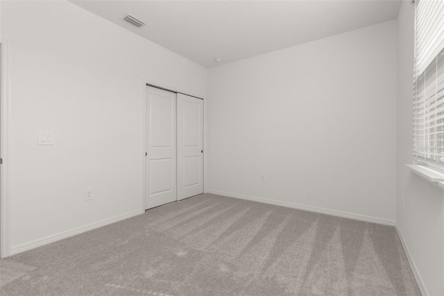 unfurnished bedroom with light carpet and a closet