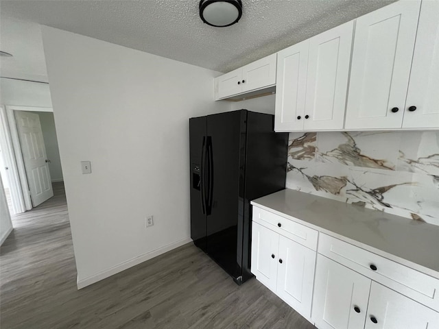 kitchen featuring decorative backsplash, white cabinets, a textured ceiling, wood-type flooring, and black fridge with ice dispenser