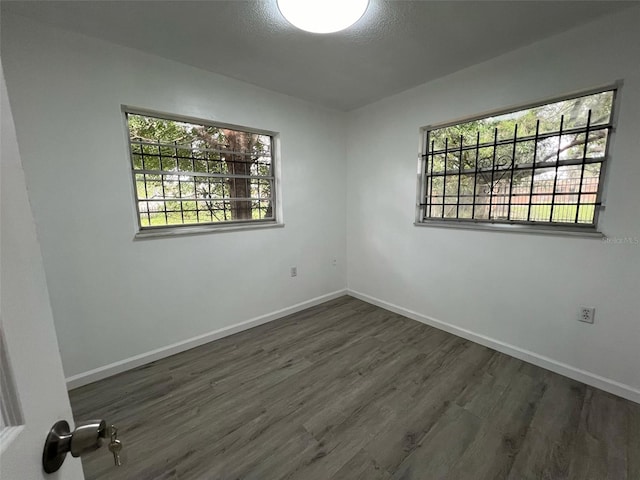 unfurnished room with a wealth of natural light and dark hardwood / wood-style flooring