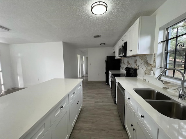 kitchen featuring appliances with stainless steel finishes, sink, a textured ceiling, dark hardwood / wood-style flooring, and white cabinetry