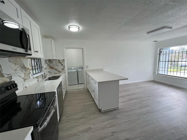 kitchen with independent washer and dryer, white cabinets, black range with electric cooktop, and light wood-type flooring