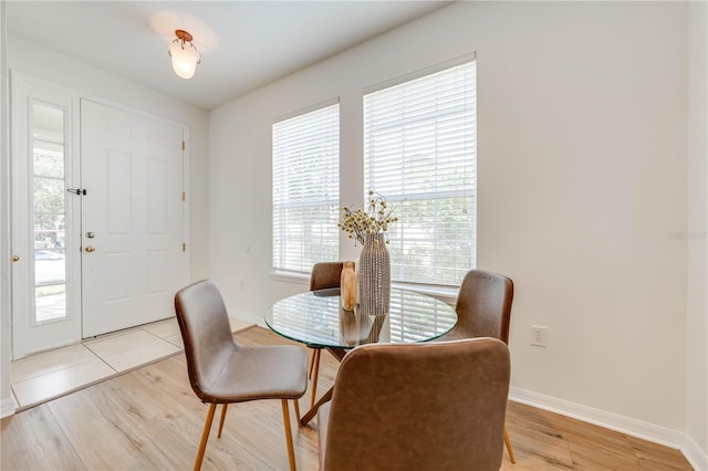 dining space with baseboards, light wood-style flooring, and a healthy amount of sunlight