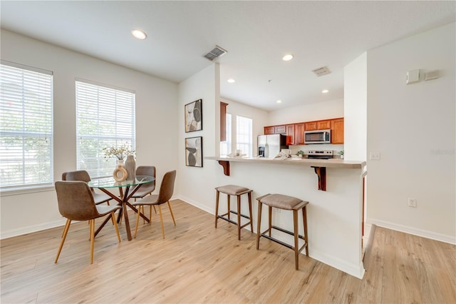 dining room featuring plenty of natural light, baseboards, visible vents, and light wood-type flooring