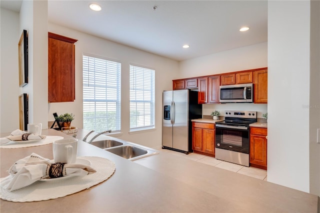 kitchen with light tile patterned floors, recessed lighting, brown cabinetry, stainless steel appliances, and a sink