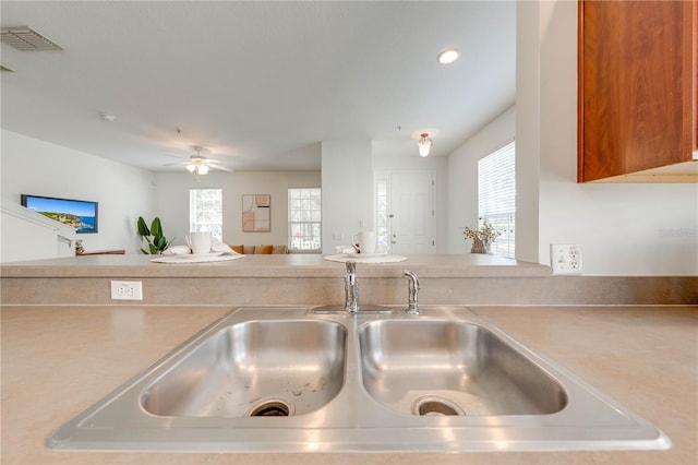 kitchen with open floor plan, light countertops, a ceiling fan, and a sink