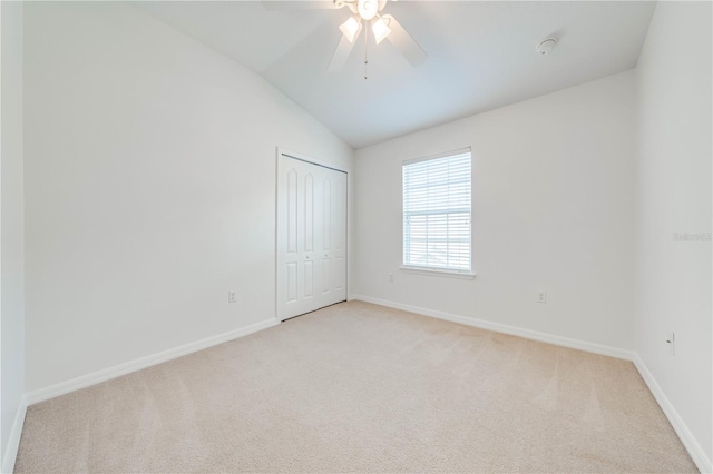 unfurnished bedroom featuring lofted ceiling, light colored carpet, baseboards, and a closet