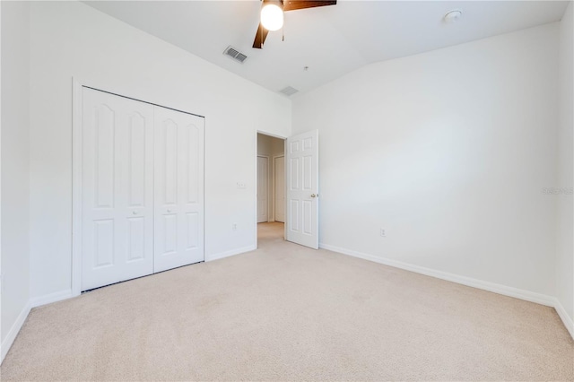 unfurnished bedroom featuring ceiling fan, a closet, light carpet, and lofted ceiling