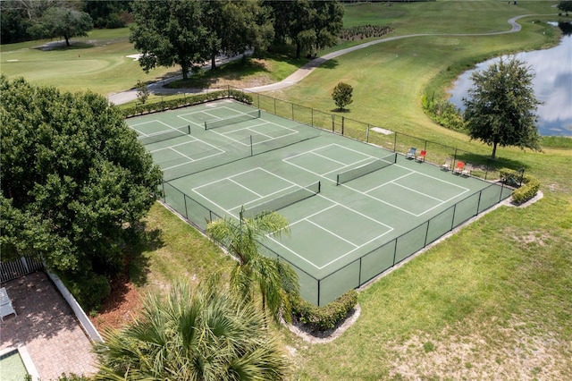 view of sport court with a water view and a lawn