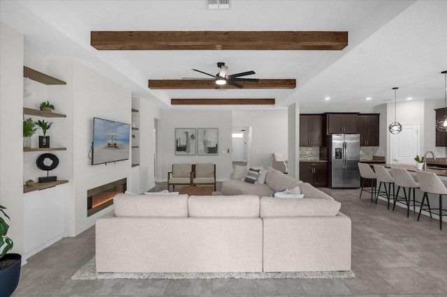 tiled living room featuring beam ceiling and ceiling fan