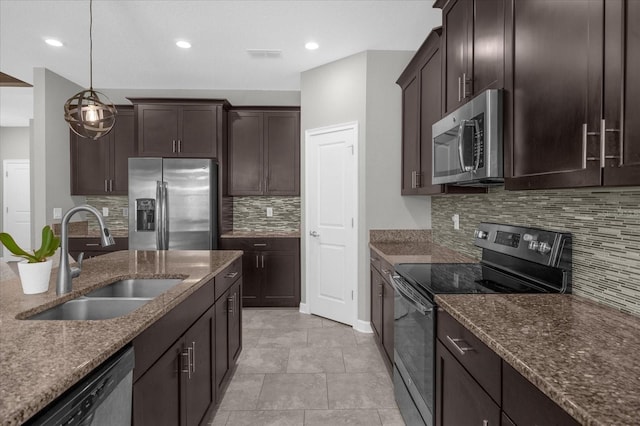 kitchen with appliances with stainless steel finishes, sink, stone countertops, dark brown cabinets, and pendant lighting