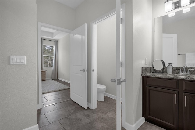 bathroom with toilet, vanity, and tile patterned floors