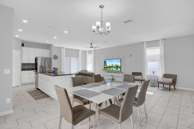 dining space featuring sink and ceiling fan with notable chandelier