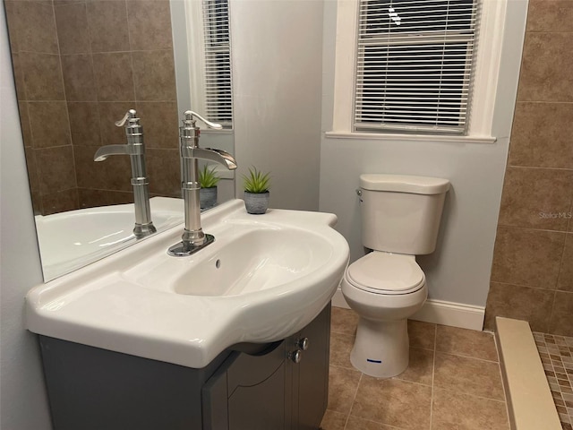 bathroom with vanity, tile patterned flooring, baseboards, and toilet