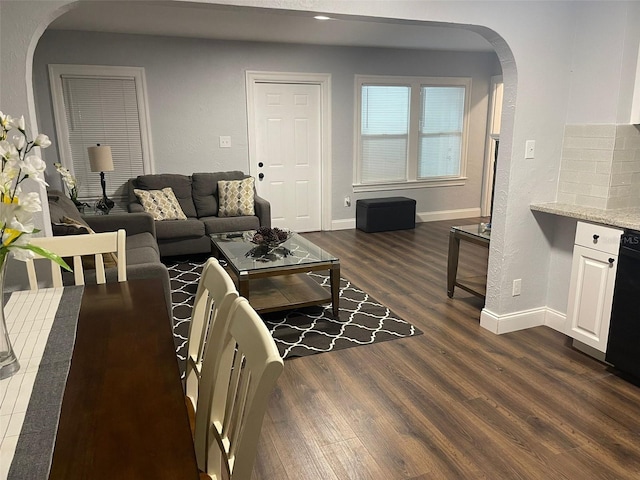 living area with arched walkways, baseboards, recessed lighting, and dark wood-type flooring