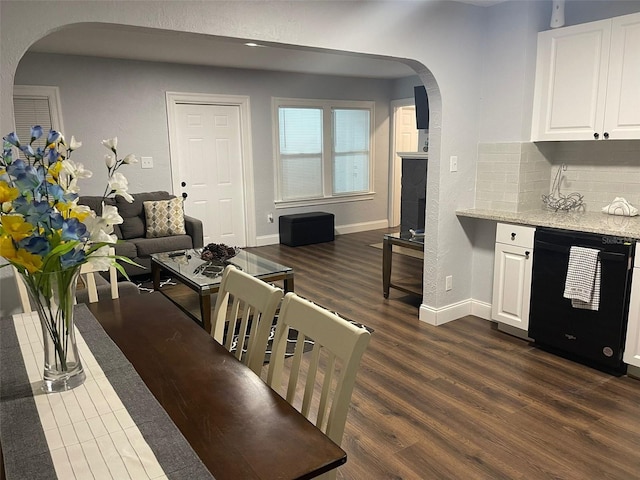 kitchen with arched walkways, light stone countertops, dark wood finished floors, dishwasher, and white cabinetry