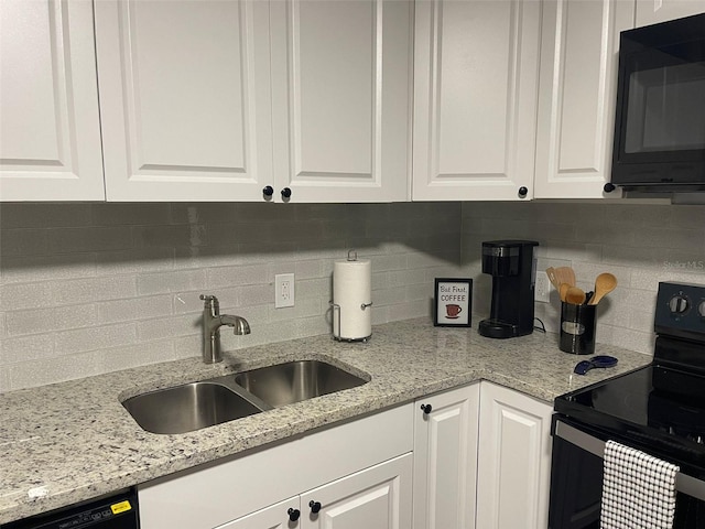 kitchen with light stone countertops, black appliances, sink, white cabinetry, and decorative backsplash