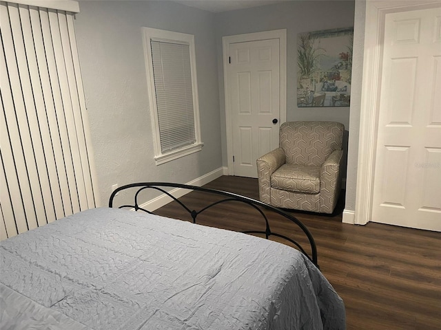 bedroom featuring baseboards and dark wood-type flooring