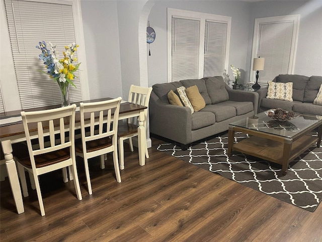 living area featuring arched walkways and wood finished floors