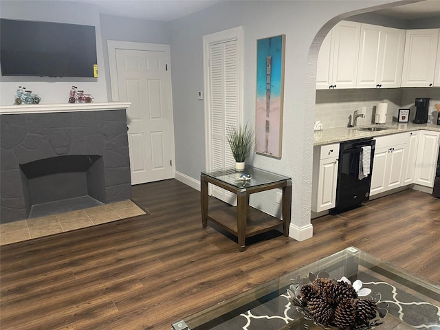 kitchen with white cabinetry, black dishwasher, dark wood-type flooring, and a fireplace