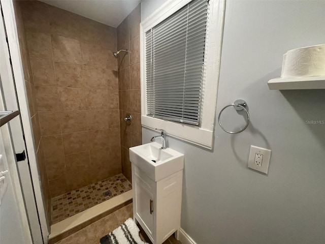 bathroom with a tile shower and vanity